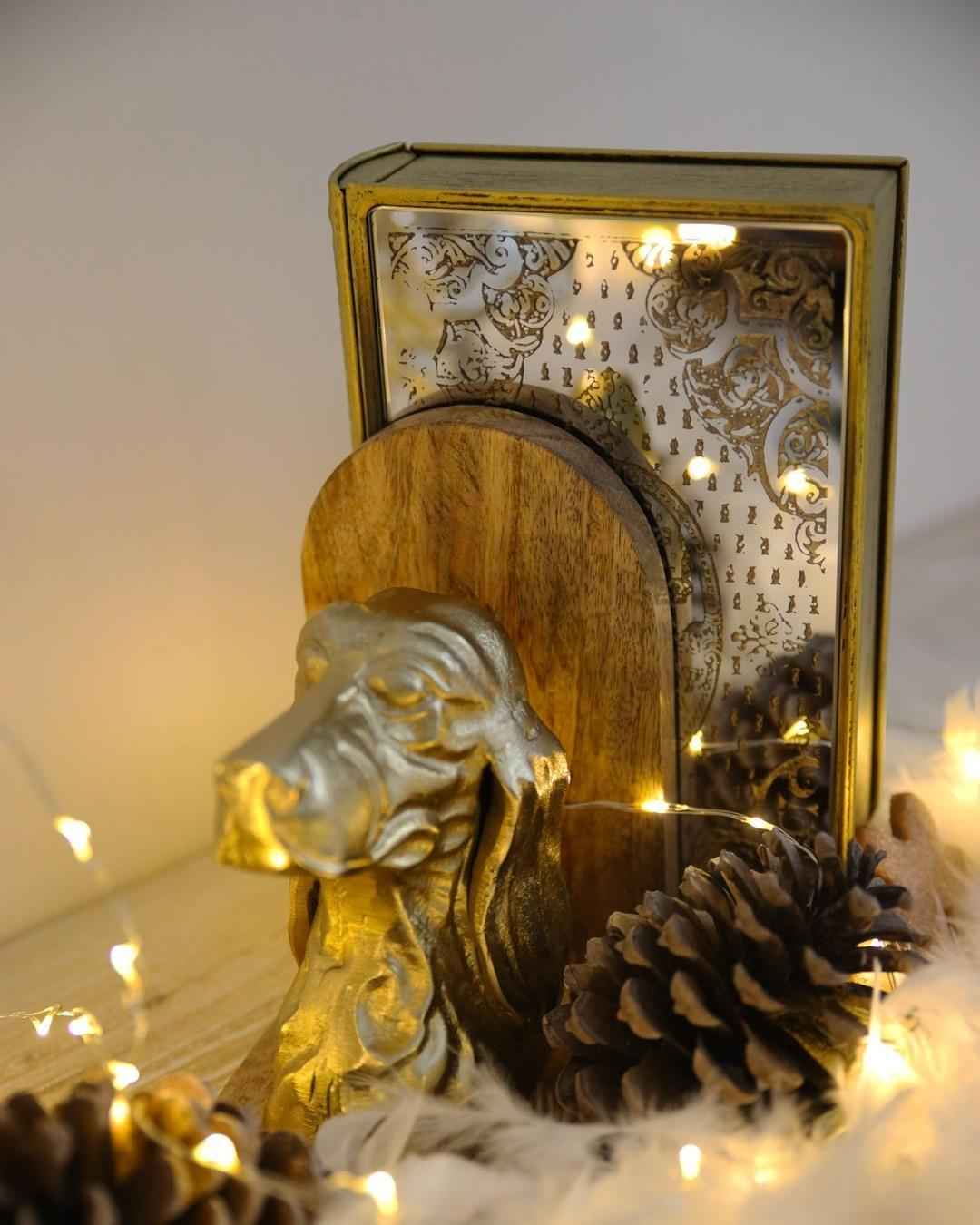 Sujetalibros con forma de busto de perro de metal dorado sobre soporte de madera